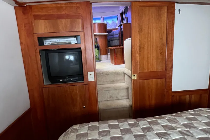 Slide: The Image of 2002 Silverton 453 Motor Yacht interior with TV, wooden cabinetry, and carpeted stairs. - 24
