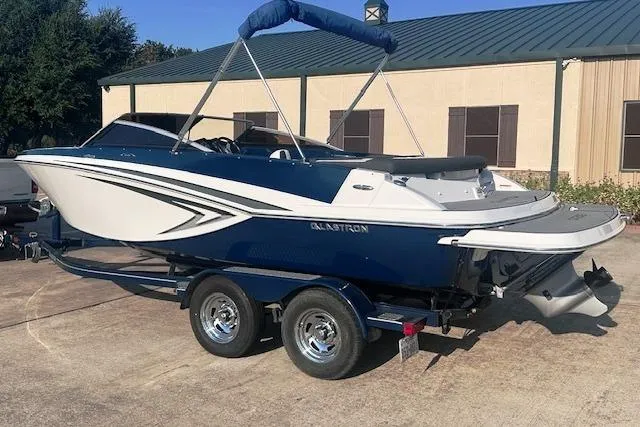 Slide: The Image of 2017 Glastron GT 205 boat on trailer, blue and white design, parked outdoors. - 1