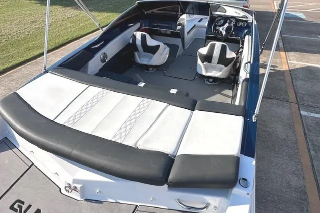 Slide: The Image of 2017 Glastron GT 205 boat interior with seating and steering wheel, docked on concrete. - 10