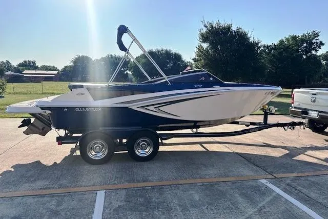 Slide: The Image of 2017 Glastron GT 205 boat on trailer in sunny outdoor setting. - 2