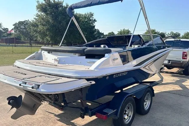 Slide: The Image of 2017 Glastron GT 205 boat on trailer, parked outdoors, with blue and white design. - 3