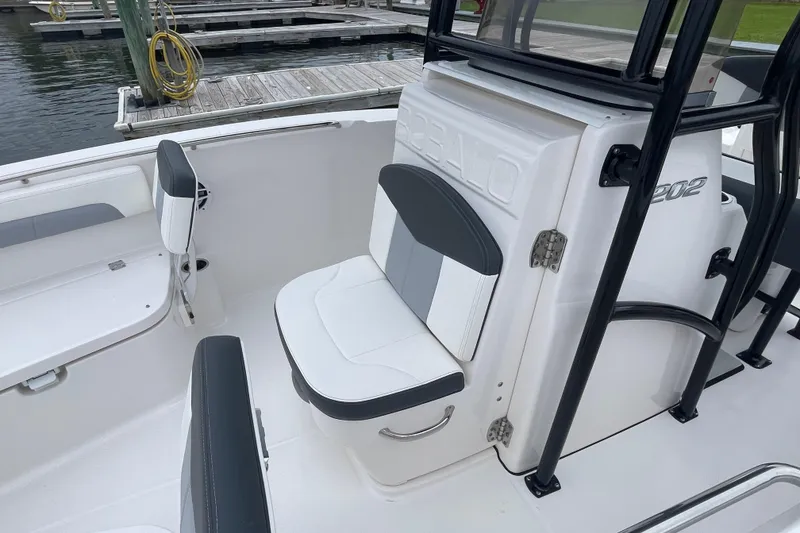 Slide: The Image of 2024 Robalo R202 Explorer boat interior with white and gray seating at a dock. - 15