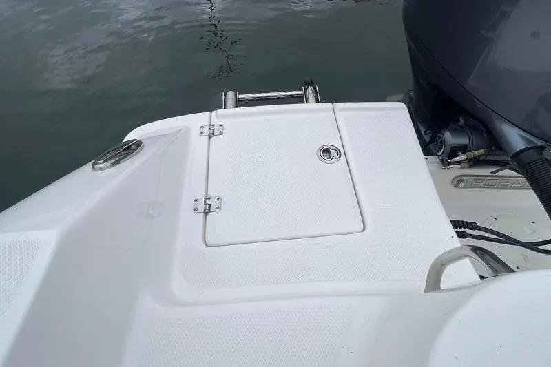 Slide: The Image of 2024 Robalo R202 Explorer boat deck with hatch and motor, on calm water. - 25
