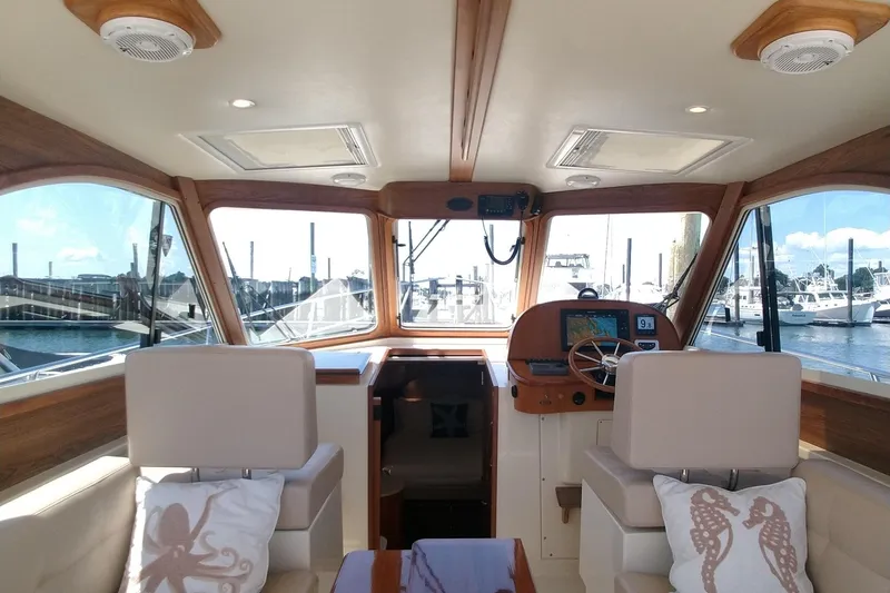 Slide: The Image of Interior of 2008 Legacy Yachts 32, featuring helm and seating with nautical decor. - 25