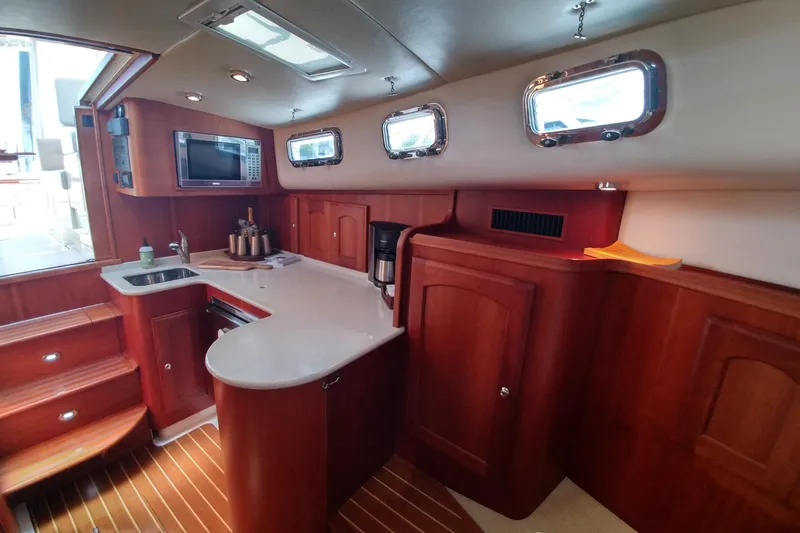 Slide: The Image of Interior of 2008 Legacy Yachts 32, featuring a compact kitchen with wood cabinetry. - 57