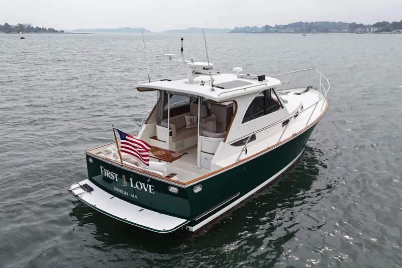 Slide: The Image of 2008 Legacy Yachts 32 on water, displaying American flag, named "First Love." - 8