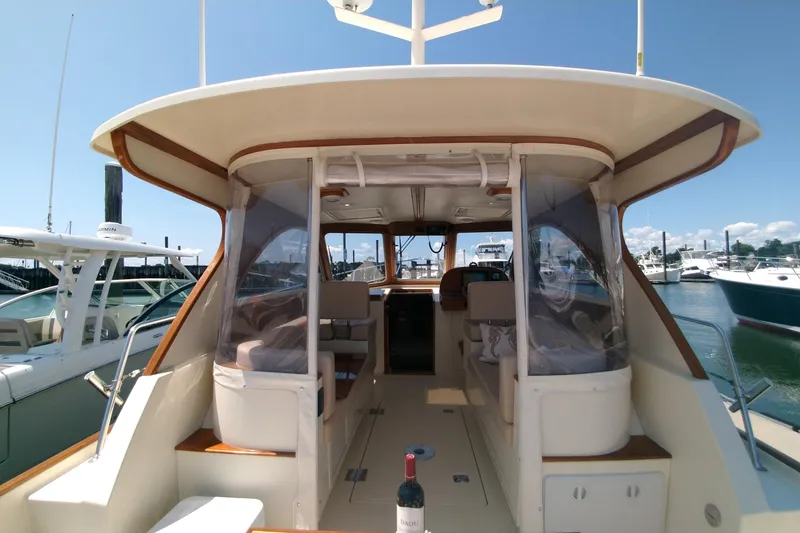 Slide: The Image of 2008 Legacy Yachts 32 interior view at marina, featuring seating and a bottle of wine. - 83