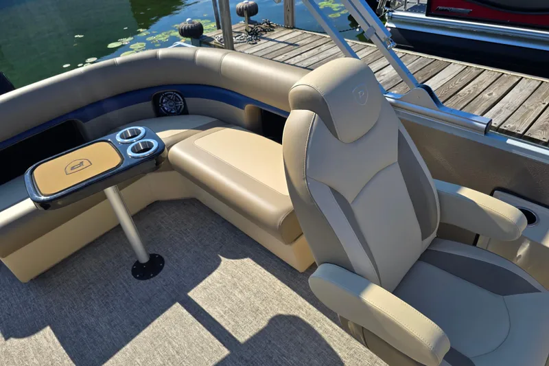 Slide: The Image of Luxurious seating on 2025 Premier 210 SunSation RE pontoon boat with cup holders and table. - 10