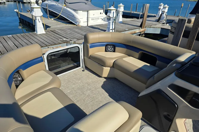Slide: The Image of 2025 Premier 210 SunSation RE pontoon boat interior with beige seating at a dock. - 8