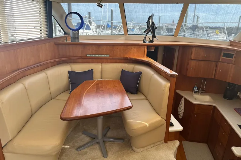 Slide: The Image of Interior of 2005 Silverton 42 Convertible yacht with beige seating and wooden table. - 33