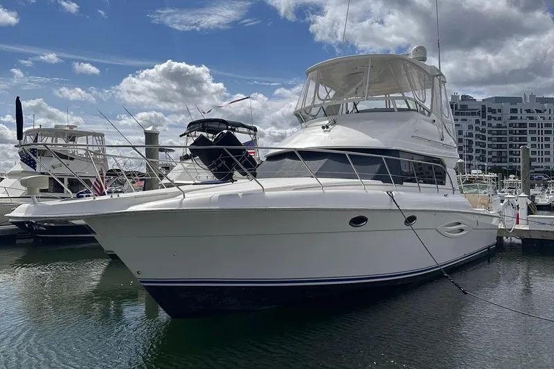 Slide: The Image of 2005 Silverton 42 Convertible yacht docked at marina under cloudy sky. - 52