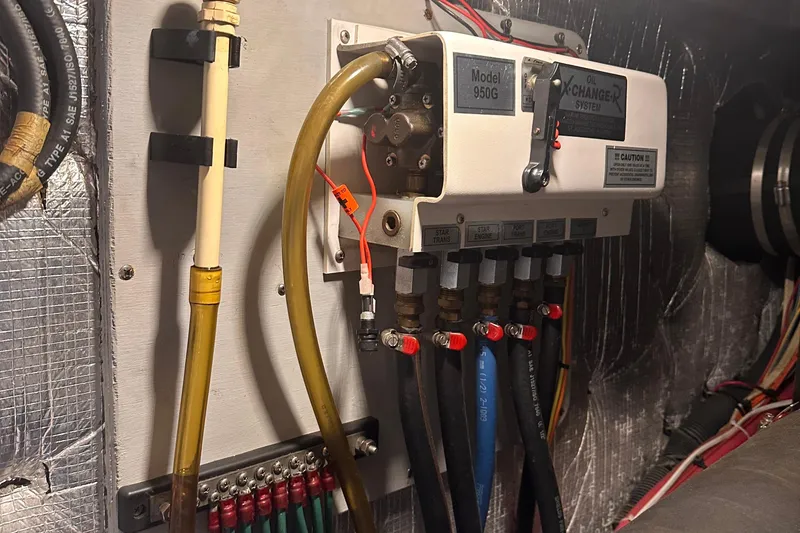 Slide: The Image of 2004 Silverton 42 Convertible engine room with oil exchanger system, Model 950G, and connected hoses. - 69