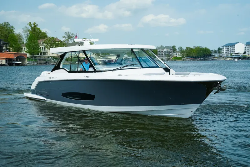 Slide: The Image of 2025 Regal LX43 boat cruising on a scenic lake with waterfront homes. - 20