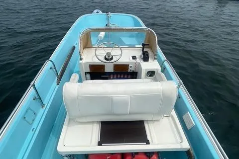 Slide: The Image of 1964 Boston Whaler 17 Montauk boat with blue interior on calm water. - 11