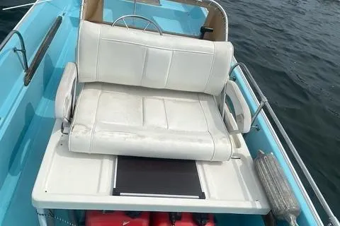 Slide: The Image of 1964 Boston Whaler 17 Montauk boat interior with white seating and blue accents on water. - 13