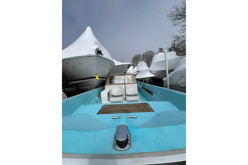 Slide: The Image of 1964 Boston Whaler 17 Montauk boat, light blue interior, stored outdoors with other covered boats. - 15