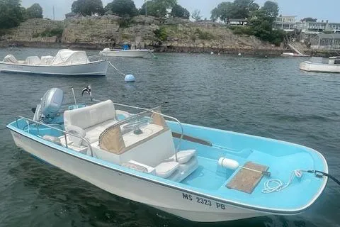 Slide: The Image of 1964 Boston Whaler 17 Montauk boat on water, rocky shoreline in background. - 5