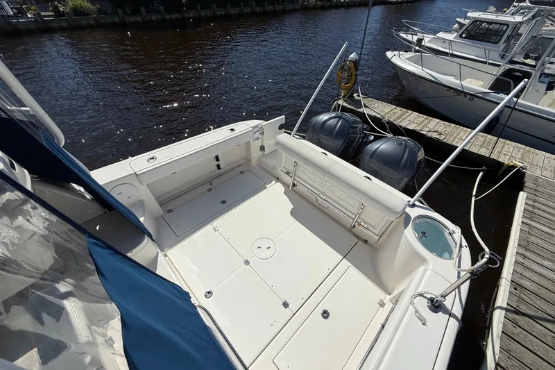 Slide: The Image of 2015 Robalo R305 Walkaround boat docked, featuring spacious deck and dual outboard engines. - 7