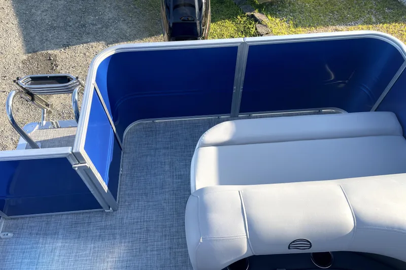 Slide: The Image of 2026 Sun Tracker Fishin' Barge 22 DLX interior with blue panels and gray seating. - 14