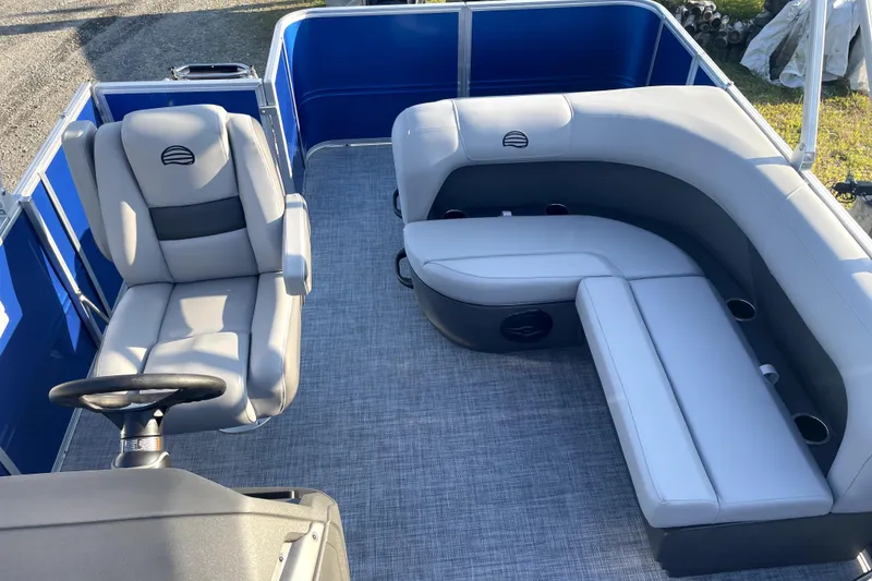 Slide: The Image of 2026 Sun Tracker Fishin' Barge 22 DLX interior with gray seating and steering wheel. - 19