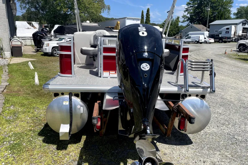 Slide: The Image of 2026 Sun Tracker Fishin' Barge 22 DLX pontoon boat with outboard motor, parked outdoors. - 4