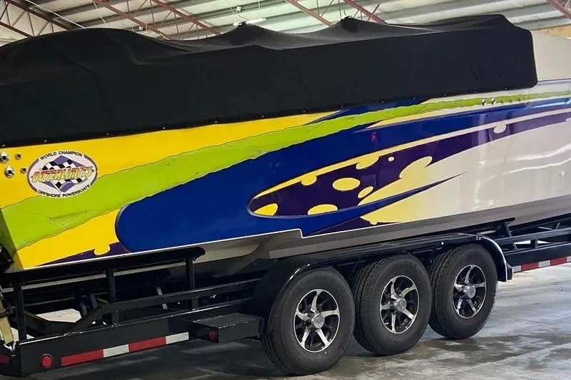 Slide: The Image of 1999 Outerlimits 37 Stiletto boat with vibrant graphics on a trailer in a garage. - 5