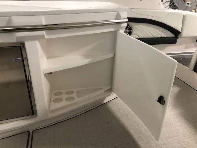 Slide: The Image of 2020 Regal 3300 Bowrider interior storage compartment with open door and cup holders. - 20