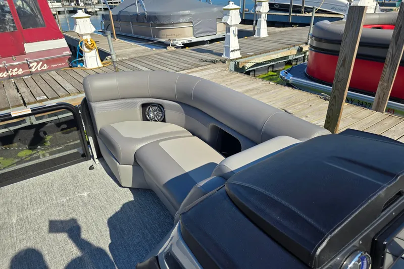 Slide: The Image of 2025 Premier 210 Sunsation RF pontoon boat with luxurious seating at a marina dock. - 13