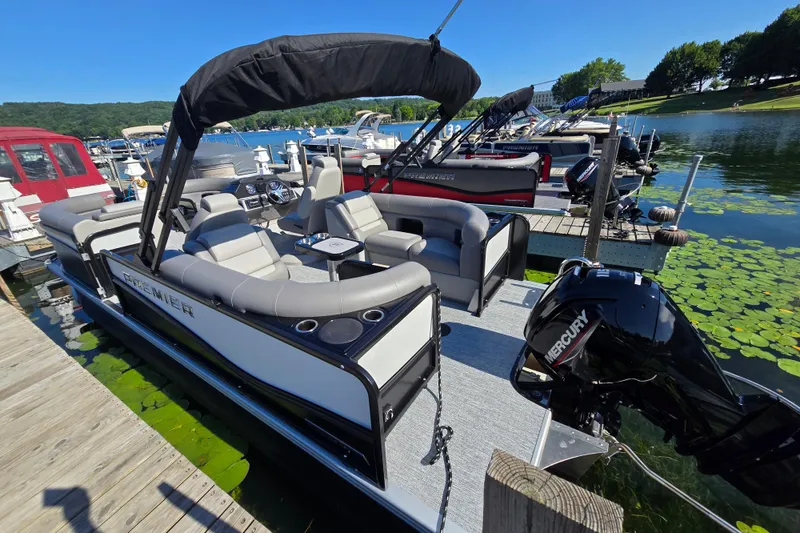 Slide: The Image of 2025 Premier 210 Sunsation RF pontoon boat docked on a sunny lake. - 4