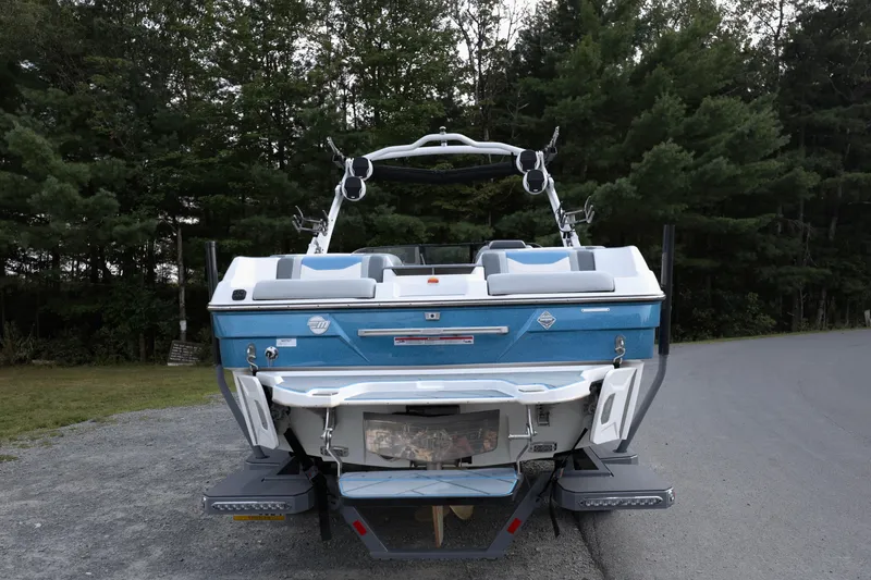 Slide: The Image of 2024 Malibu Wakesetter 23 LSV boat, rear view, parked near forested area. - 3