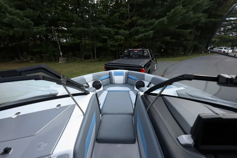 Slide: The Image of 2024 Malibu Wakesetter 23 LSV interior with truck in background, near forested area. - 8