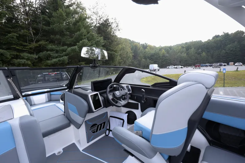 Slide: The Image of 2024 Malibu Wakesetter 23 LSV interior with modern dashboard and seating, parked near forest. - 9