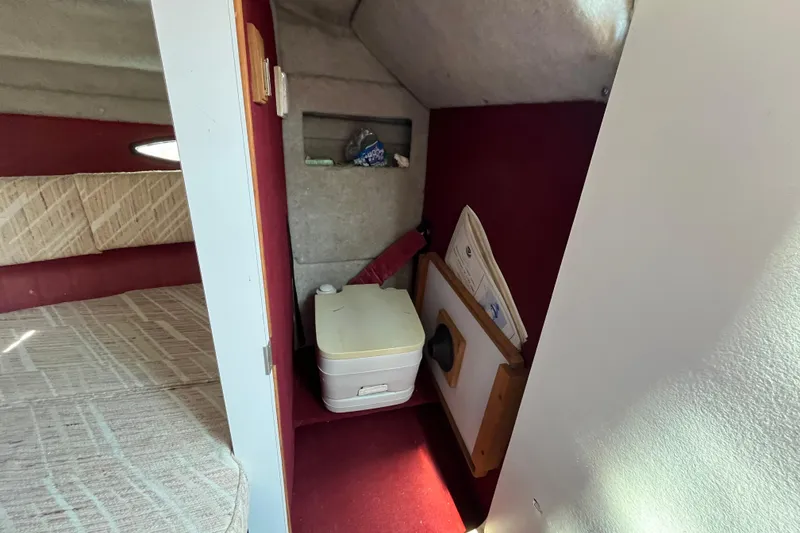 Slide: The Image of 1988 Four Winns 235 Sundowner cabin interior with portable toilet and storage area. - 15