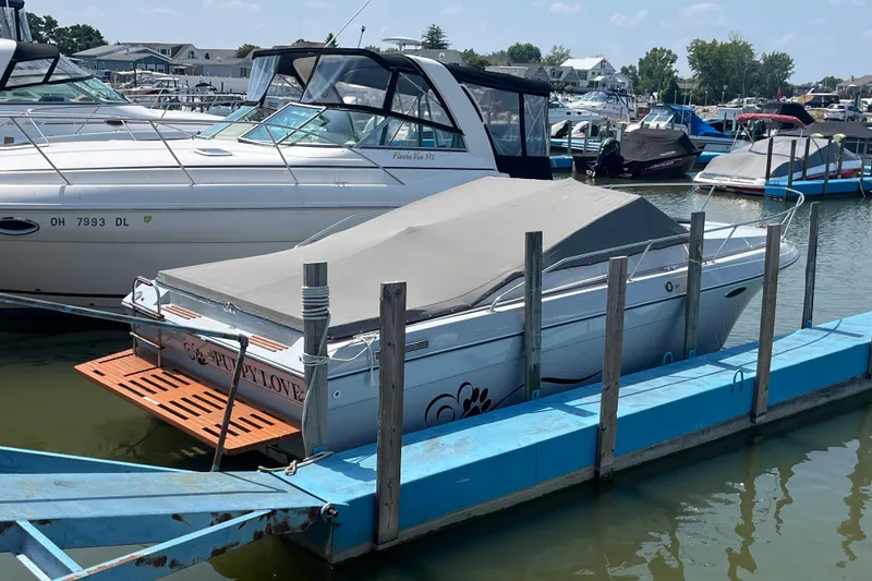 Slide: The Image of 1988 Four Winns 235 Sundowner boat docked with cover, surrounded by other boats. - 22