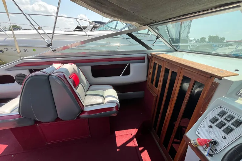 Slide: The Image of 1988 Four Winns 235 Sundowner boat interior with red and white seating, wooden cabinetry, and control panel. - 6