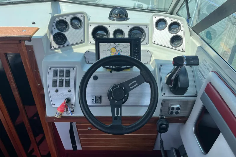 Slide: The Image of 1988 Four Winns 235 Sundowner boat dashboard with steering wheel and navigation controls. - 9