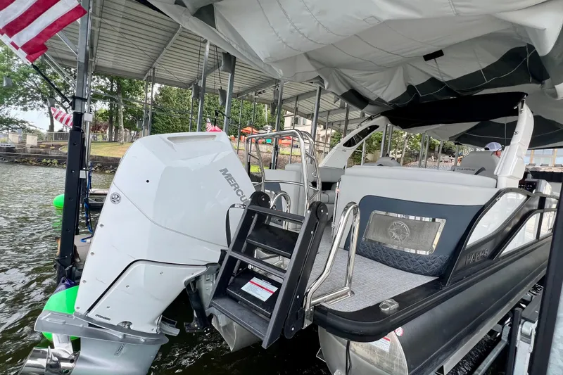Slide: The Image of 2025 Harris Grand Mariner 250 pontoon boat docked with Mercury outboard engine. - 31