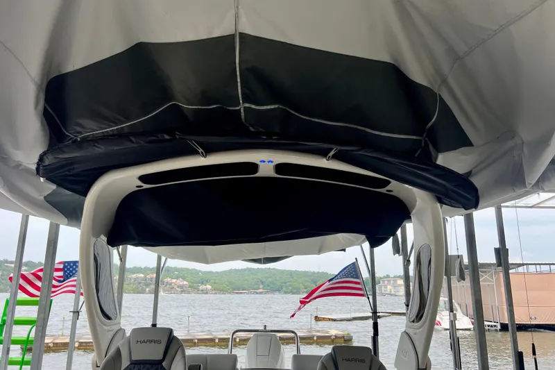 Slide: The Image of 2025 Harris Grand Mariner 250 boat interior with American flags and lake view. - 7