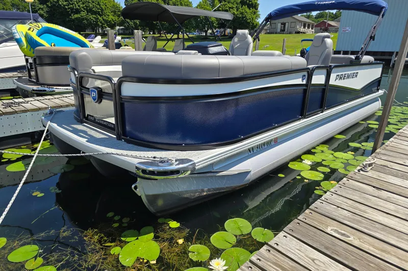 Slide: The Image of 2025 Premier 230 Sunsation RE pontoon boat docked on a sunny day. - 4