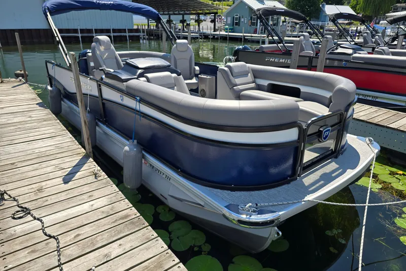 Slide: The Image of 2025 Premier 230 Sunsation RE pontoon boat docked on a sunny day. - 5