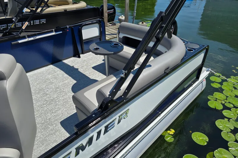 Slide: The Image of 2025 Premier 230 Sunsation RE pontoon boat with seating and table, docked on a lake. - 8