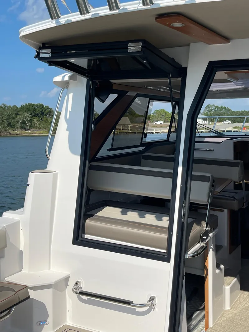 Slide: The Image of 2026 Cutwater C-288 Coupe boat interior with open door, showcasing seating and water view. - 8