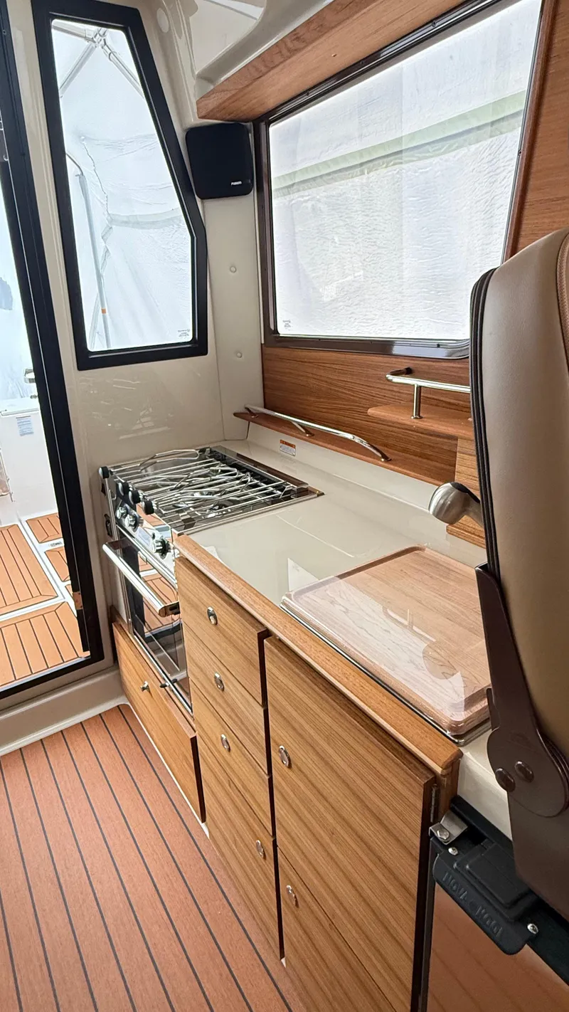 Slide: The Image of 2026 Ranger Tugs R-27 interior kitchen with stove, wooden cabinetry, and modern design. - 33