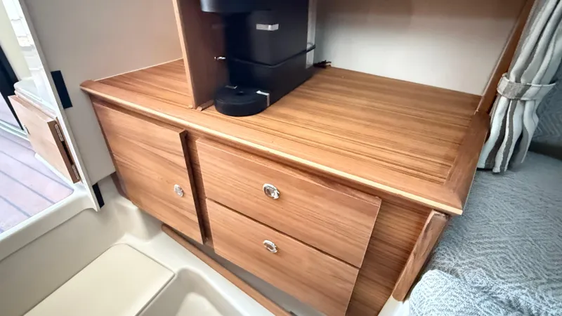 Slide: The Image of Interior of 2026 Ranger Tugs R-27 with wooden cabinetry and coffee maker. - 42