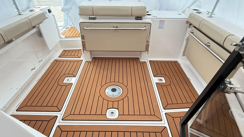 Slide: The Image of 2026 Ranger Tugs R-27 boat interior with teak-style flooring and beige seating. - 9