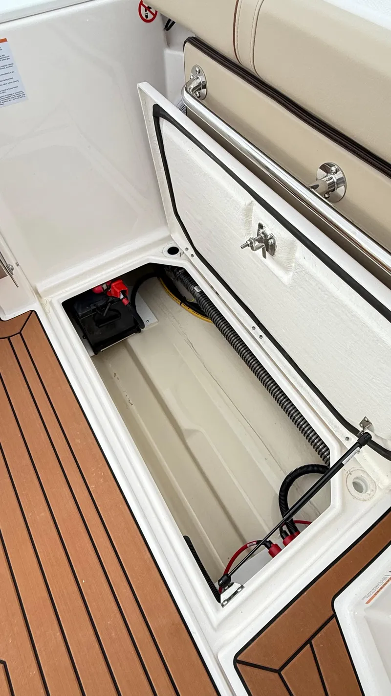Slide: The Image of Open storage compartment on 2026 Ranger Tugs R-27 boat with visible wiring and battery. - 14