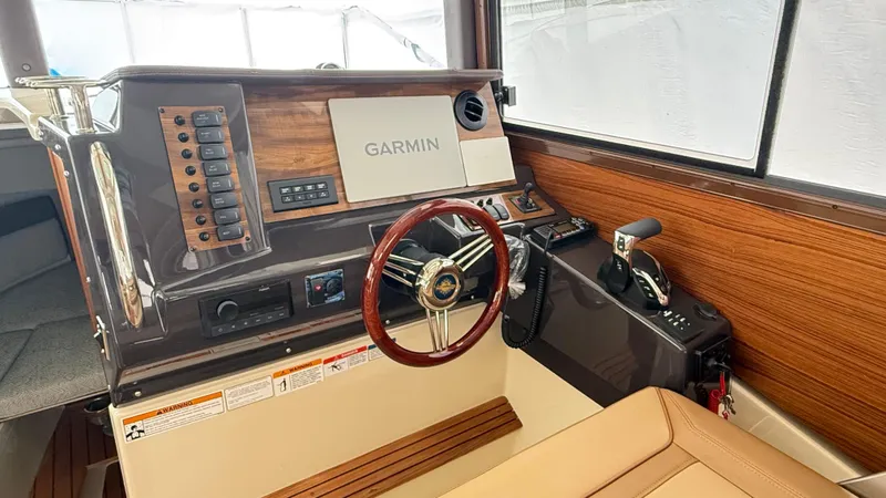 Slide: The Image of 2026 Ranger Tugs R-27 helm with Garmin navigation, wood accents, and leather seating. - 18