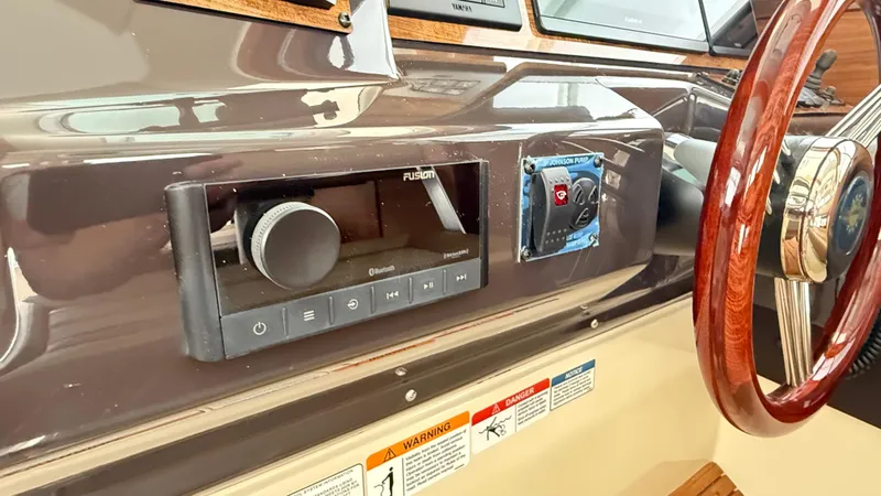 Slide: The Image of 2026 Ranger Tugs R-27 dashboard with Fusion audio system and wooden steering wheel. - 25