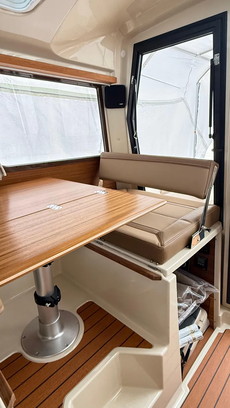 Slide: The Image of 2026 Ranger Tugs R-27 interior with wooden table and cushioned seating. - 32