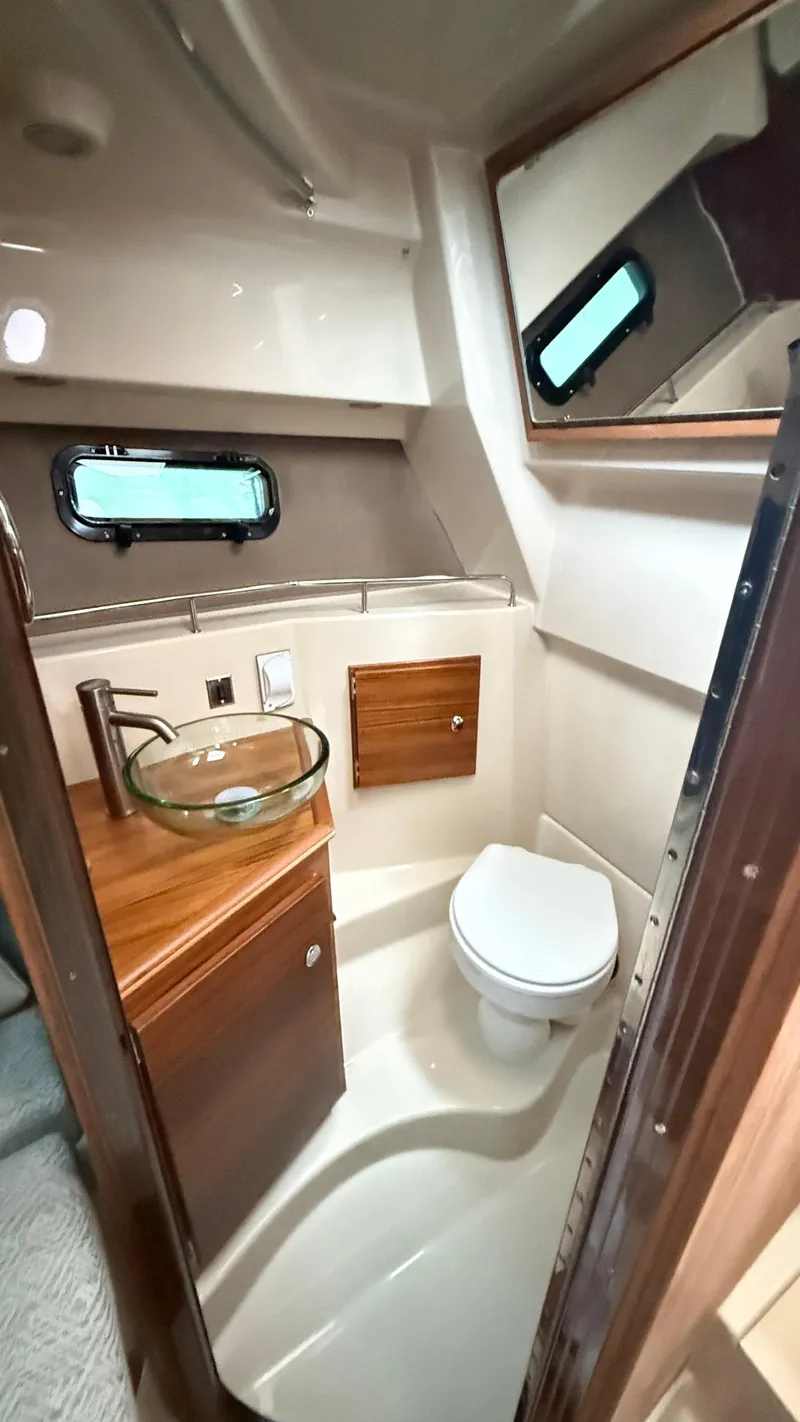 Slide: The Image of 2026 Ranger Tugs R-27 boat bathroom with modern fixtures and wooden cabinetry. - 46
